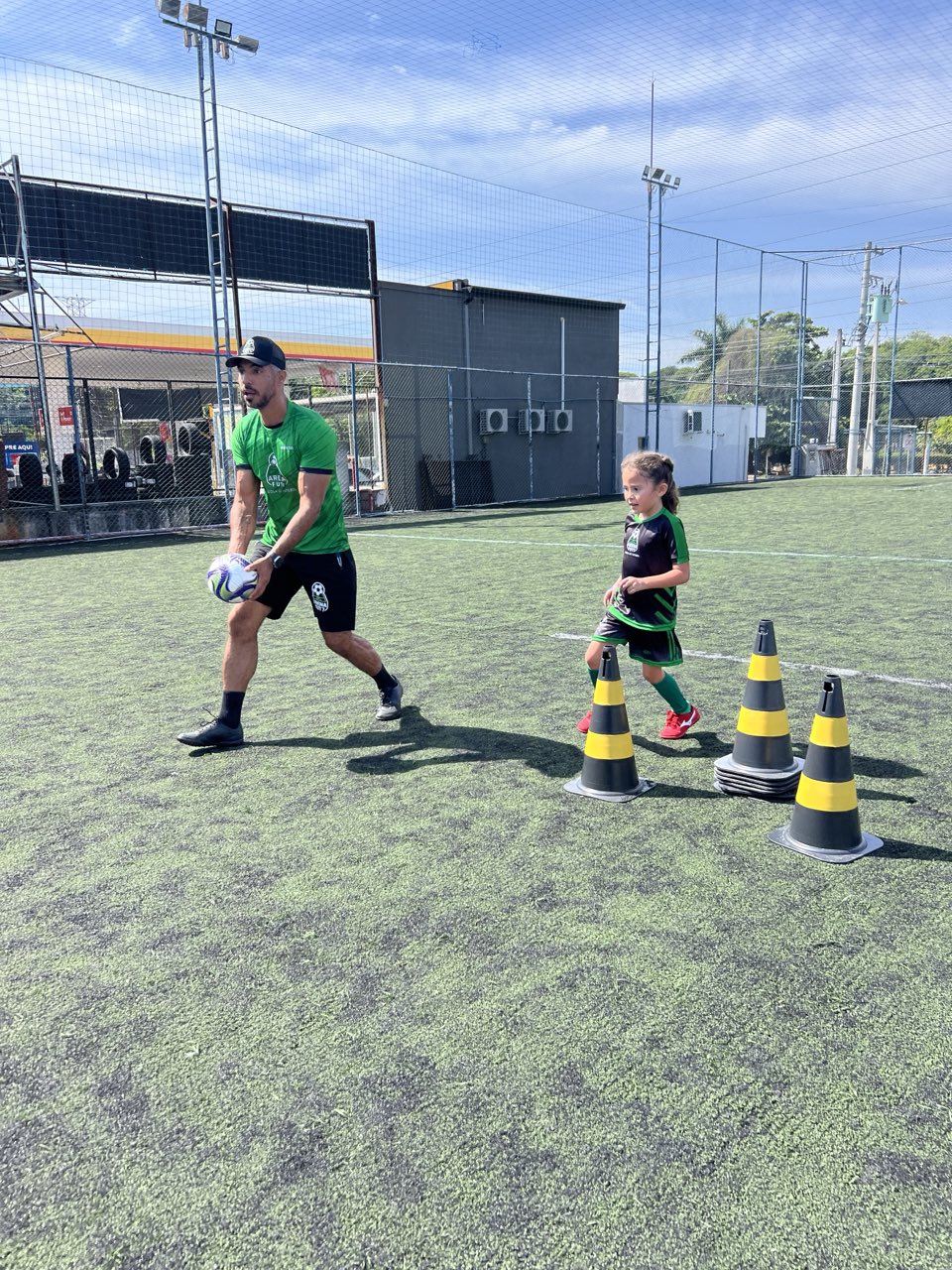 Professor da Arena Fut7 conduzindo aluno em exercício com cones